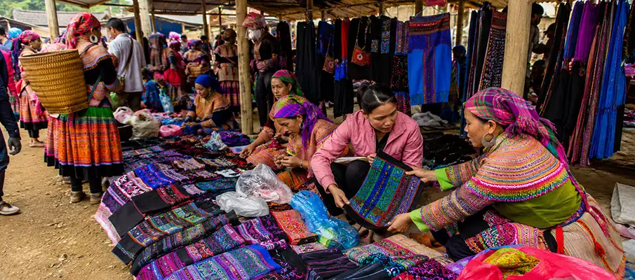 Flower H'Mong women selling colorful handmade textiles at Coc Ly Market near Bac Ha, Vietnam