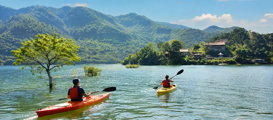 Kayaking on Hoa Binh Lake in Northern Vietnam Tourists kayaking on the calm waters of Hoa Binh Lake surrounded by mountains in northern Vietnam