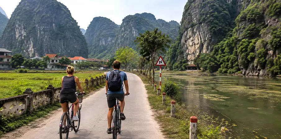 Tourists cycling through the scenic countryside of Trang An Scenic Landscape Complex in Ninh Binh, Vietnam.